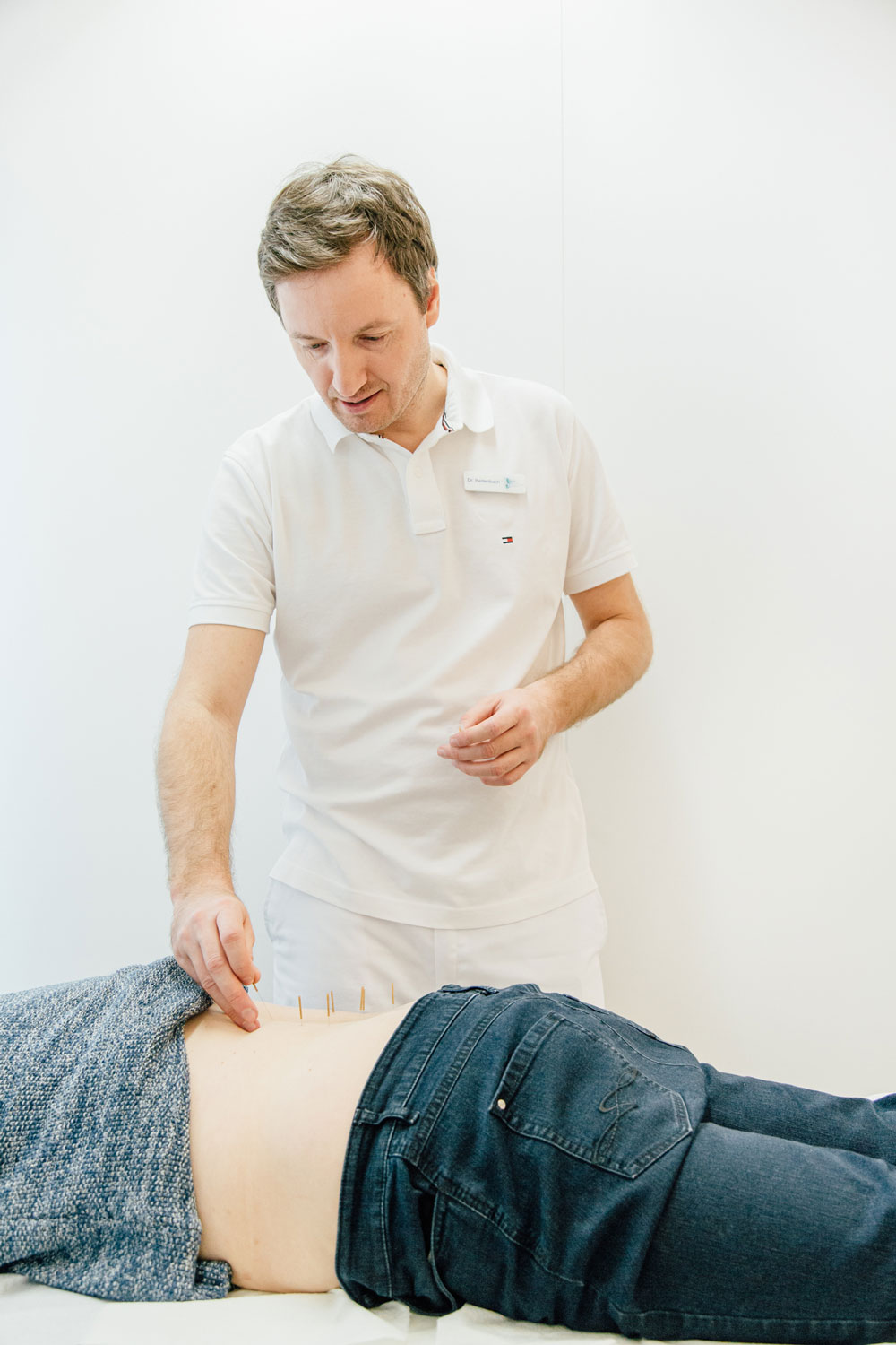 Akupunktur Bensberg - Dr. Reitenbach setzt feine Nadeln in Rücken von Patientin